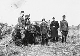 A group of cavalry officers in front of a camouflaged 75mm Puteaux gun model 1897/36